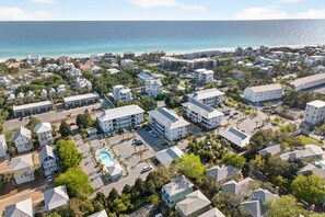 An aerial view of a coastal residential area with multiple buildings, a parking lot, and a swimming pool. - Hidden Lake 622 – Coastal Luxury Condo with Community Pool (Santa Rosa Beach)