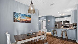 Eine moderne Küche mit weißen Schränken, einem Holztisch und einem großen Gemälde an der Wand.