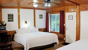 Une chambre confortable dans un chalet, avec un lit, un bureau doté d’un micro-ondes et une fenêtre avec des rideaux.