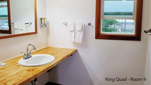 Une salle de bain avec un meuble-lavabo en bois, un lavabo blanc, un miroir et une fenêtre donnant sur un beau paysage.