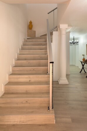 A wooden staircase with a handrail, white walls, and a chandelier in the background. - Charming Villa with Pool and 3 Suites (Paúl do Mar)