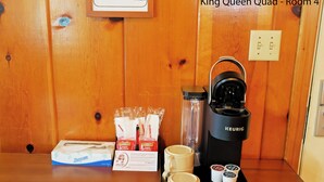 Une machine à café Keurig, deux tasses, une boîte de mouchoirs et un paquet de mouchoirs sur une table en bois.