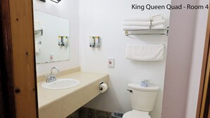 Une salle de bain équipée d’un lavabo, d’un miroir, de toilettes et d’un porte-serviettes.