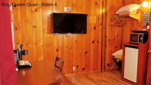Une cuisine compacte avec un mur en bois, un téléviseur à écran plat, un four à micro-ondes et un petit réfrigérateur.