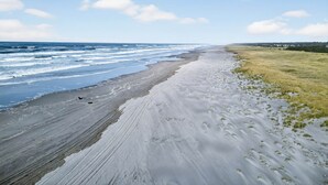 A beach with a wide sandy area and a grassy field.