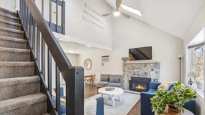 Ein geräumiger Wohnbereich mit Kamin, Treppe und großem Fenster.
