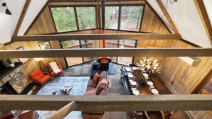 Una stanza con soffitto alto, un'area da pranzo, posti a sedere e vista sull'esterno.