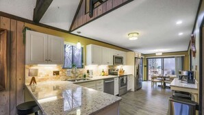 Una cucina moderna con ripiani in granito, elettrodomestici in acciaio inossidabile e un'area pranzo con vista.