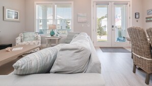 Een woonkamer met een bank, een stoel, een klein tafeltje en een raam met jaloezieën.