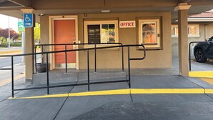 A building entrance with a ramp, a wheelchair accessibility sign, and an office sign. - Townhouse Motel (Tracy)