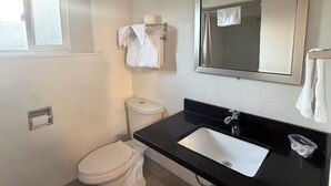 A bathroom with a toilet, sink, and mirror. - Townhouse Motel (Tracy)