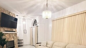 A modern living room with a stone fireplace, a large beige sofa, a round coffee table, and a flat-screen TV mounted on the wall. - ☆☀︎❀Paradise! Pool Table, Sauna, Boat Parking, Fenced Yard, Near Boat Launch (Sebastian)