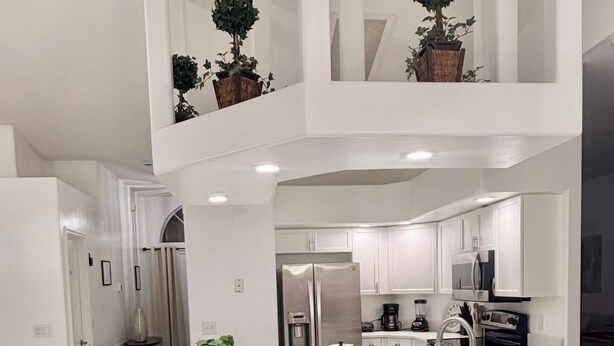 A modern kitchen with a central island, bar stools, a refrigerator, a sink, and potted plants. - ☆☀︎❀Paradise! Pool Table, Sauna, Boat Parking, Fenced Yard, Near Boat Launch (Sebastian)
