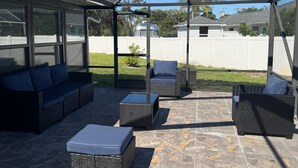 A covered patio area with outdoor furniture, a stone floor, and a view of the backyard. - ☆☀︎❀Paradise! Pool Table, Sauna, Boat Parking, Fenced Yard, Near Boat Launch (Sebastian)