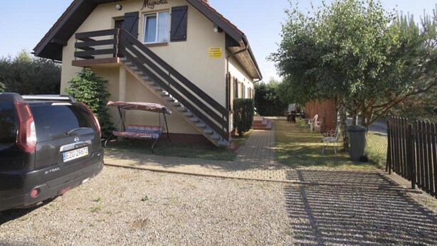 A two-story building with a staircase leading to the upper floor, a covered outdoor seating area, and a car parked in front. - Studio for 2 People, Rowy (Ustka)