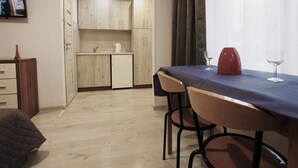 A compact living space with a kitchenette, a dining area with two chairs, and a television mounted on the wall. - Studio for 2 People, Rowy (Ustka)