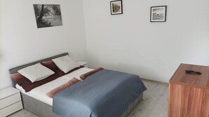 A bedroom with a bed, a nightstand, a wooden dresser, and three framed pictures on the wall. - Studio for 2 People, Rowy (Ustka)