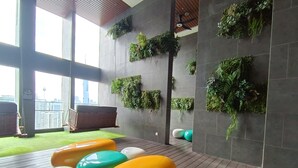 A modern interior with a wooden floor, green wall planters, and colorful seating. - KL Sentral, Kuala Lumpur, 4 pax Family Merdeka 118 Nice View, , Sky Pool MRT LRT (Kuala Lumpur)