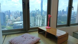 A room with a large window, a pink pillow, a small wooden table, and a pink desk lamp. - KL Sentral, Kuala Lumpur, 4 pax Family Merdeka 118 Nice View, , Sky Pool MRT LRT (Kuala Lumpur)