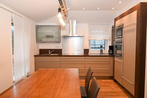 Eine moderne Küche mit einem Holzesstisch, einem eingebauten Ofen und Edelstahlgeräten.