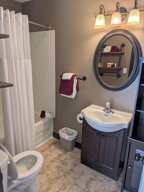 Ein Badezimmer mit Toilette, Waschbecken, Spiegel und Duschvorhang.