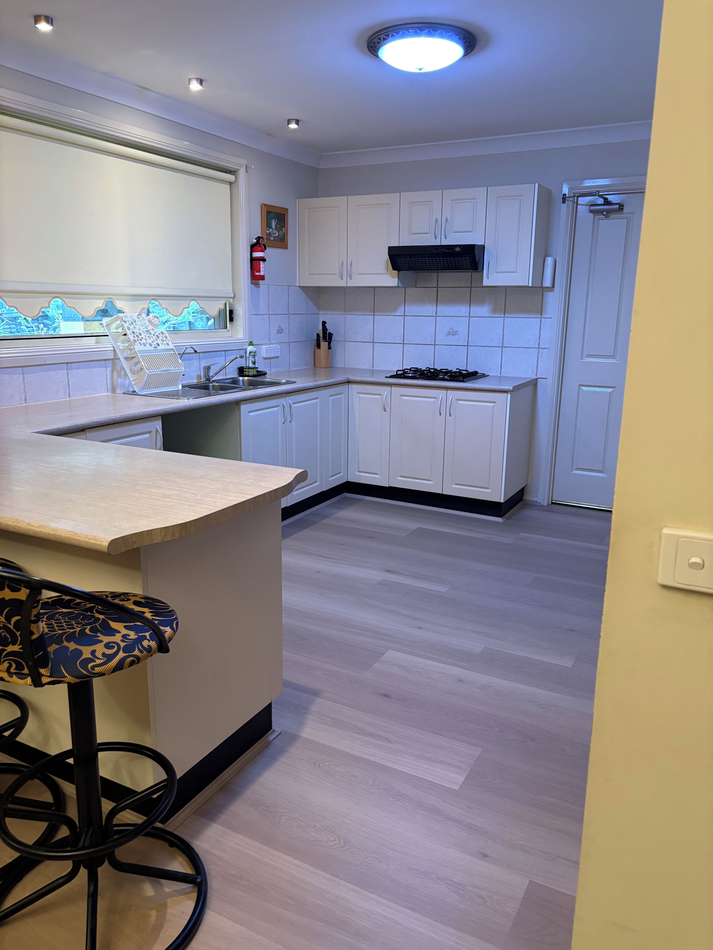 Una cocina moderna con armarios blancos, una estufa a gas y una zona de bar con taburetes.