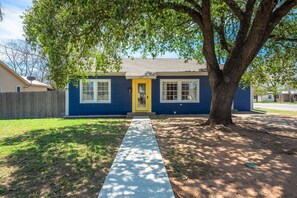 Una casa de un solo piso con fachada azul y puerta delantera amarilla.
