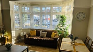 Ein gemütliches Wohnzimmer mit Erkerfenster, einer Couch, einem Couchtisch und einem Esstisch mit Stühlen.