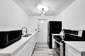 A compact kitchen with a microwave, sink, refrigerator, and oven. - Private Tampa Home Quick Drive to Attractions (Tampa)