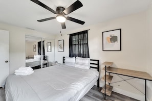 A bedroom with a bed, a desk, a ceiling fan, a mirror, and a framed picture on the wall. - Private Tampa Home Quick Drive to Attractions (Tampa)