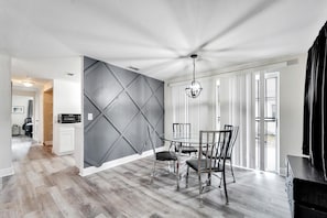 A dining area with a modern chandelier, a dining table with chairs, and a kitchen in the background. - Private Tampa Home Quick Drive to Attractions (Tampa)
