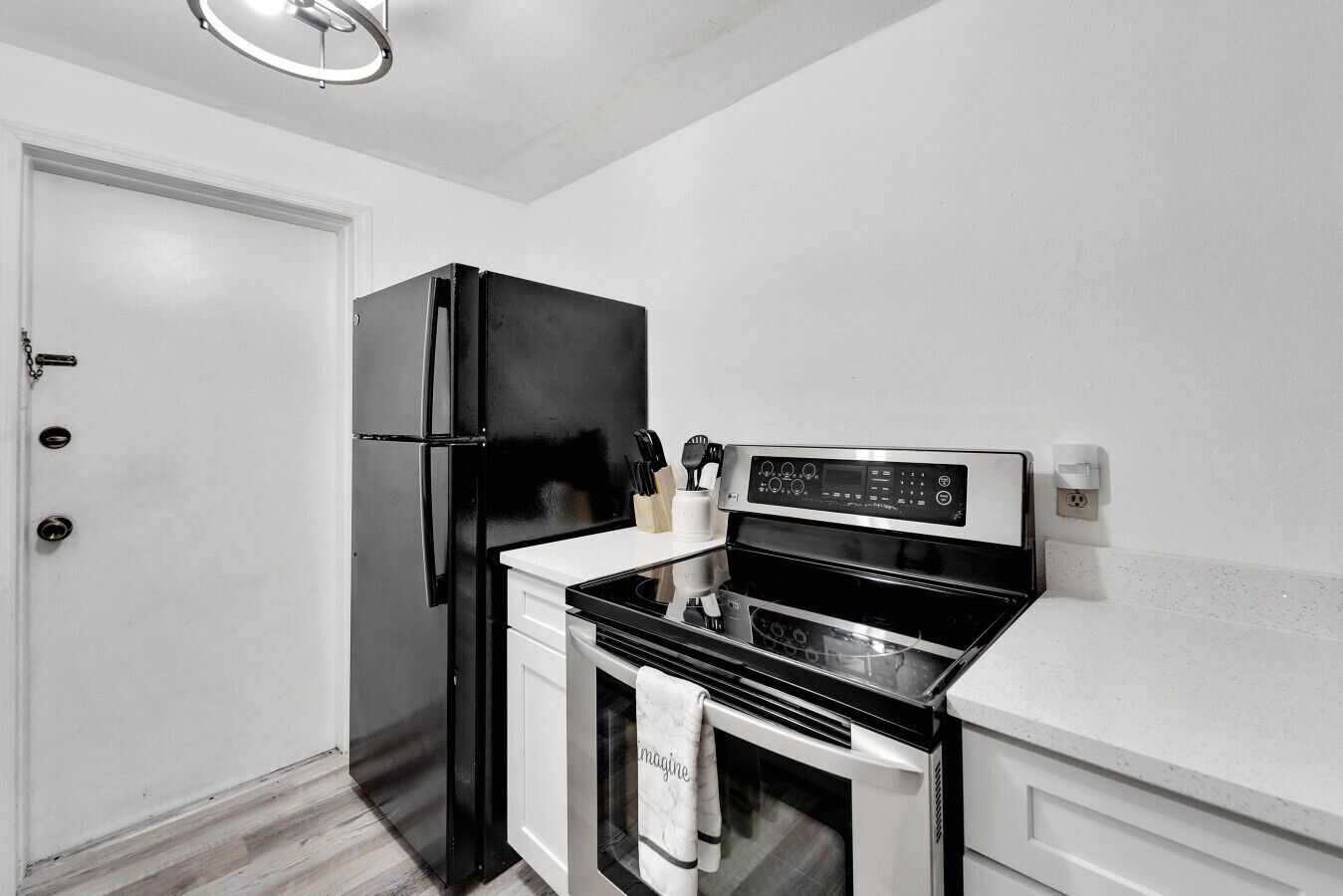 A compact kitchen with a black refrigerator, a stove, and a microwave.