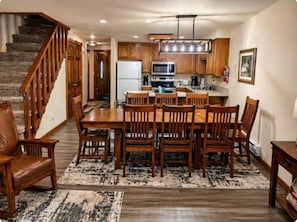 A kitchen with wooden cabinets, a dining table with chairs, a staircase, and a rug. - Cozy Mountain Retreat in the heart of McCall (McCall)