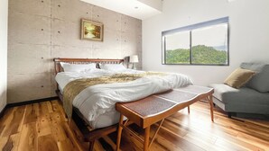 Una camera da letto con un letto, una panca, una finestra vista e un quadro appeso al muro.