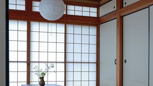 Una tradizionale stanza giapponese con pavimento in tatami, un tavolino con un vaso e porte scorrevoli.