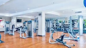 Ett gym med olika träningsmaskiner, ett trägolv och en stor spegel.