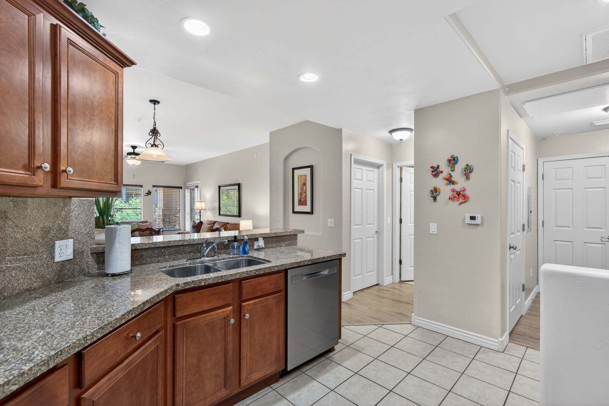 A kitchen with granite countertops, wooden cabinets, a dishwasher, and a pendant light.