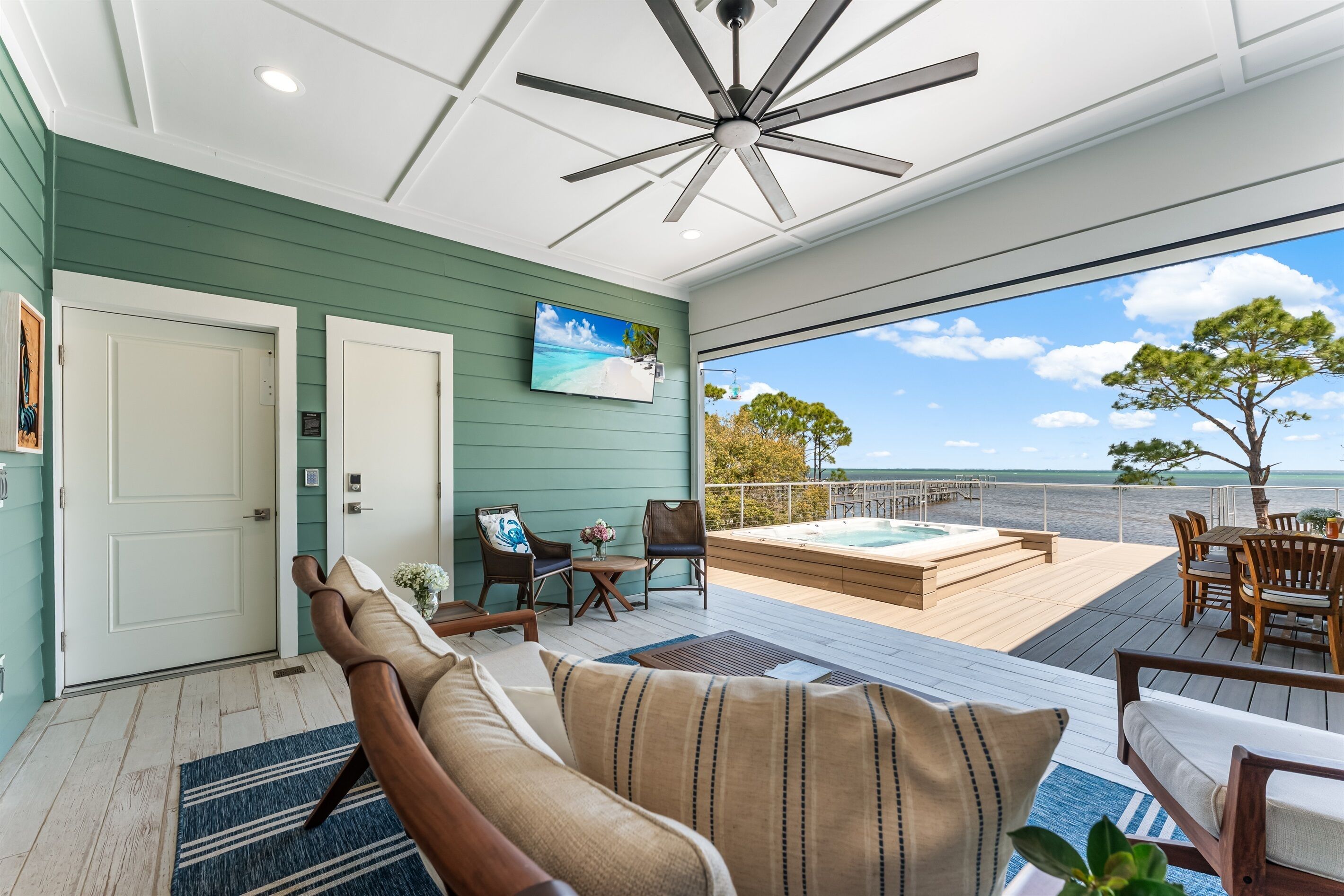 A modern interior with a ceiling fan, a TV, and a view of the ocean.