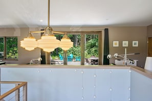 Una cucina moderna con un'ampia finestra, luci a sospensione e vista sul giardino.