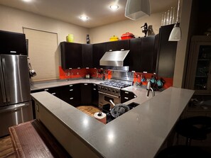 A modern kitchen with a stainless steel refrigerator, a built-in oven, and a gas stove.