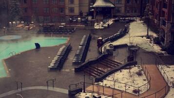 A resort with multiple swimming pools, a snow-covered landscape, and a building with a Harrah's sign.