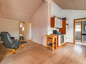 Un espacio habitable pequeño con comedor, kitchenette y una zona de estar con una silla.