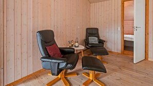 Huoneessa on kaksi nahkaista nojatuolia, pieni pöytä, jonka päällä on kynttilä, ja ovi, joka johtaa makuuhuoneeseen.