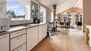 Moderni keittiö, jossa on suuri ikkuna, puulattia ja ruokailutila, jossa on pöytä ja tuolit.