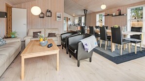 Moderni sisustus, jossa on puinen katto, sohva, ruokapöytä ja keittiötila.