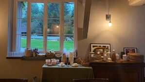 Une pièce dotée d’une grande fenêtre, d’une table où sont disposés des aliments pour le petit-déjeuner et d’un luminaire fixé au mur.