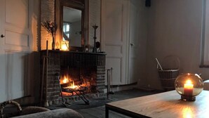 Une pièce avec une cheminée, une table avec une bougie et une chaise.