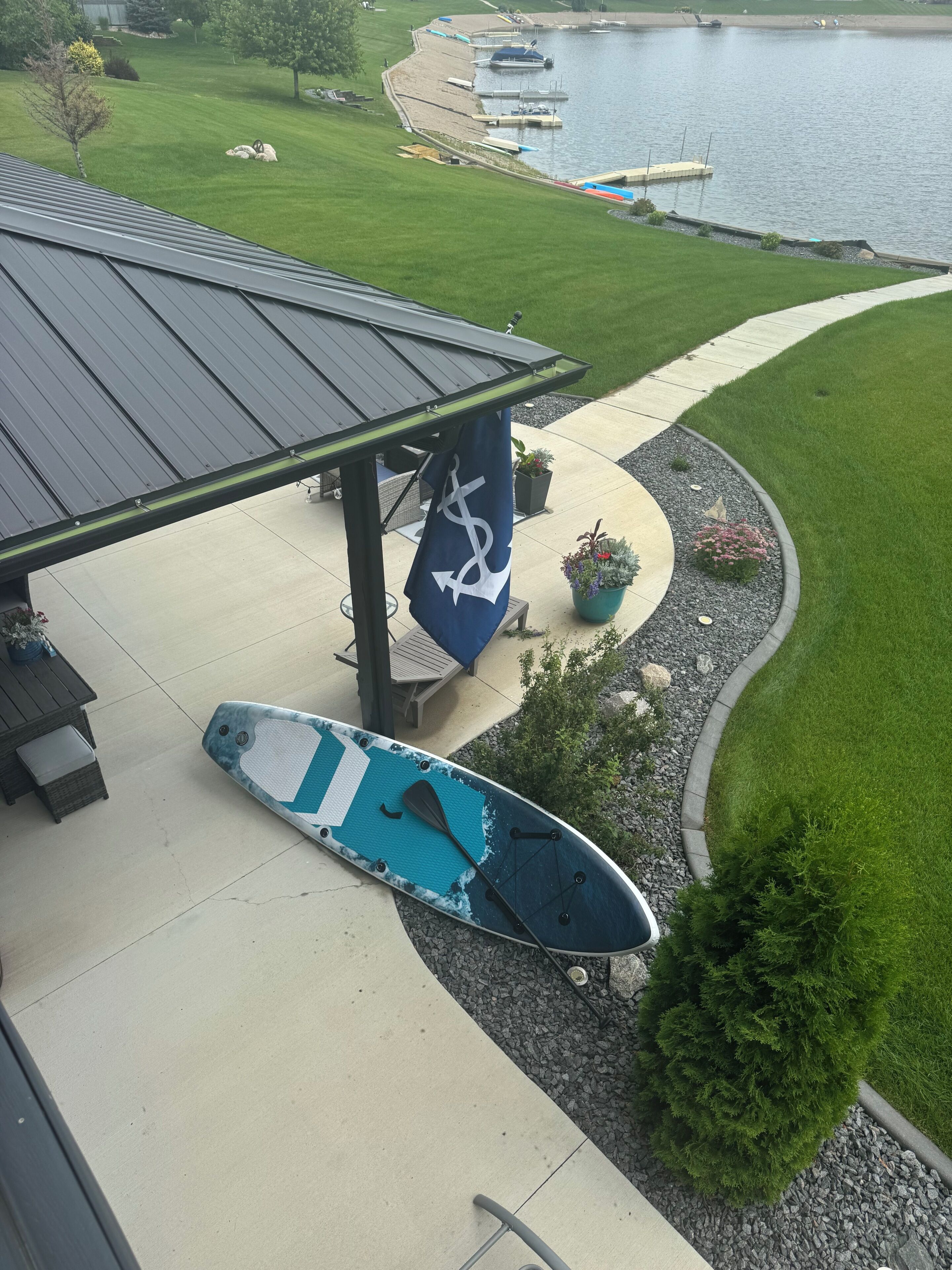 A covered outdoor area with a paddleboard, a flag, and a view of a lake with boats.