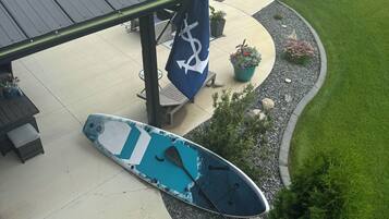 A covered outdoor area with a paddleboard, a flag, and a view of a lake with boats.