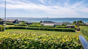Een woongebied aan de kust met keurig geknipte hagen, een heldere lucht en uitzicht op zee.